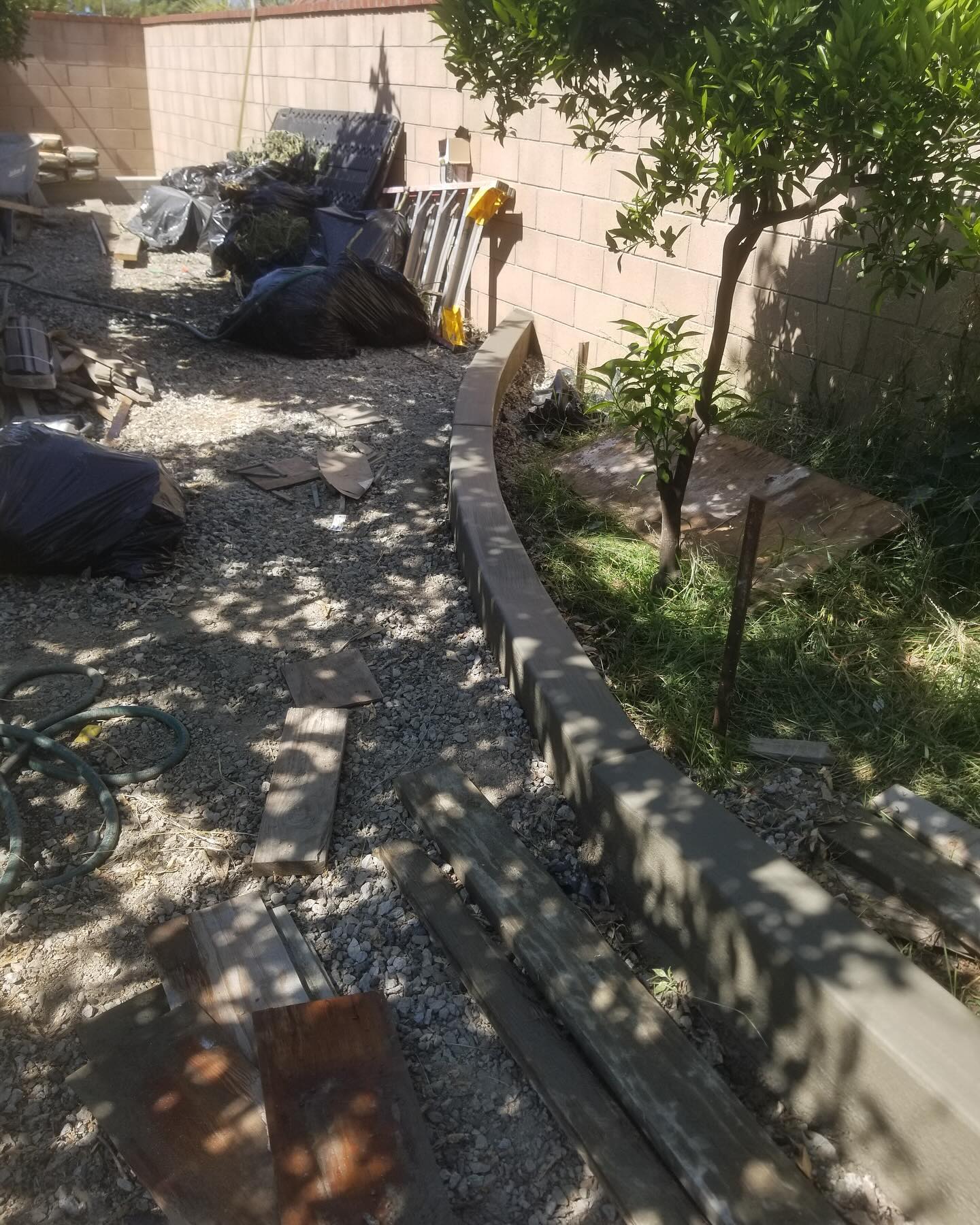 Turf installation area before curved concrete curb by Mountain Ridge Renovations